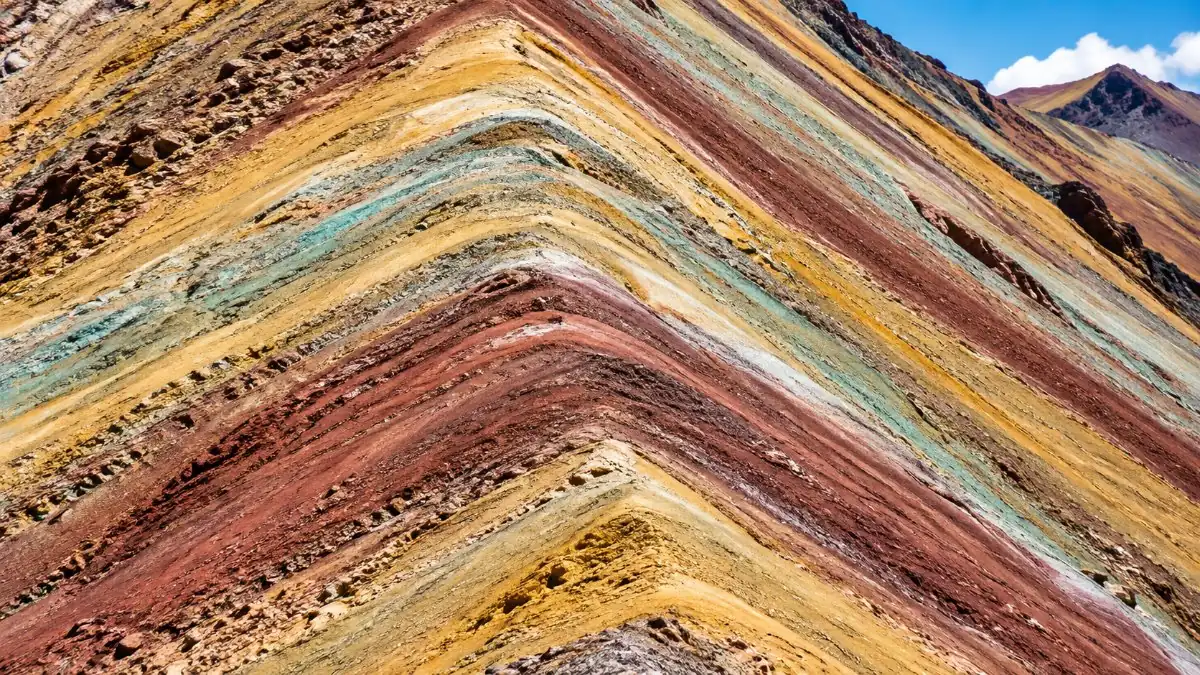 Nahaufnahme der gestreiften Hänge von Vinicunca mit roten, ockerfarbenen, grünen und weißen Streifen