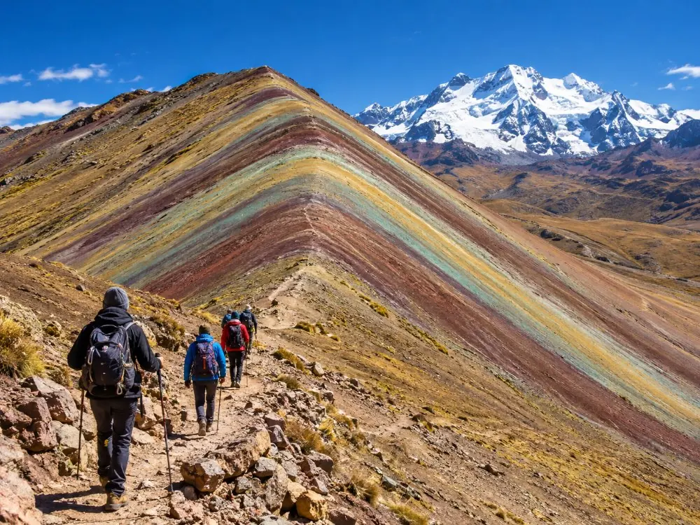 Wanderer auf der letzten Serpentine, die zum gestreiften Grat von Vinicunca hinaufklettern
