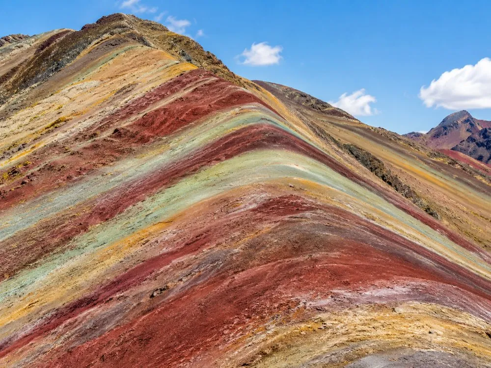 Nahaufnahme der roten, senffarbenen, grünen und lavendelfarbenen Mineralstreifen am Berghang